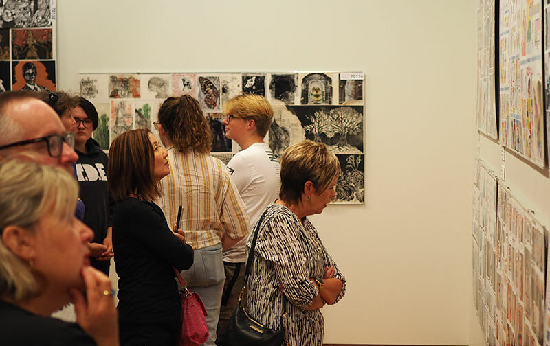 A crowd of people in a gallery admires artworks
